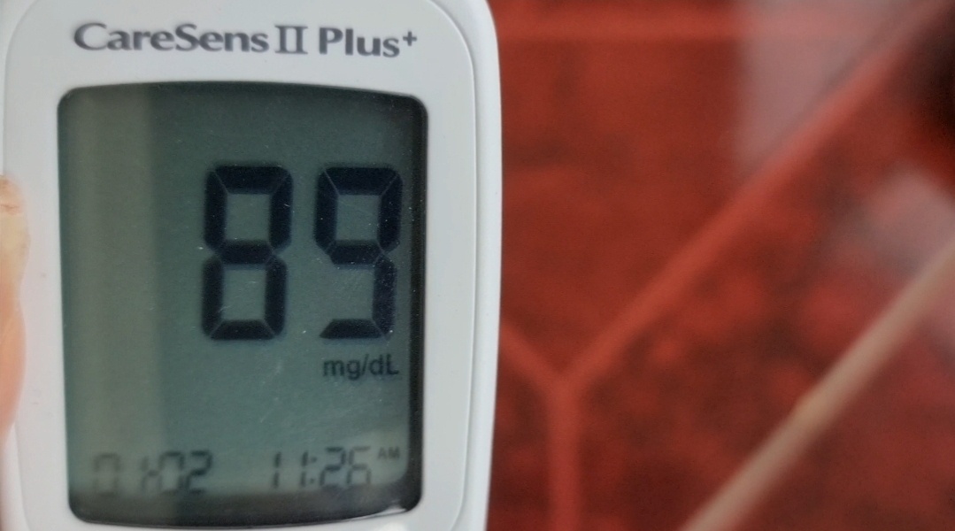 A recent photo of a blood glucose meter showing a healthy reading of 89 mg/dL.
