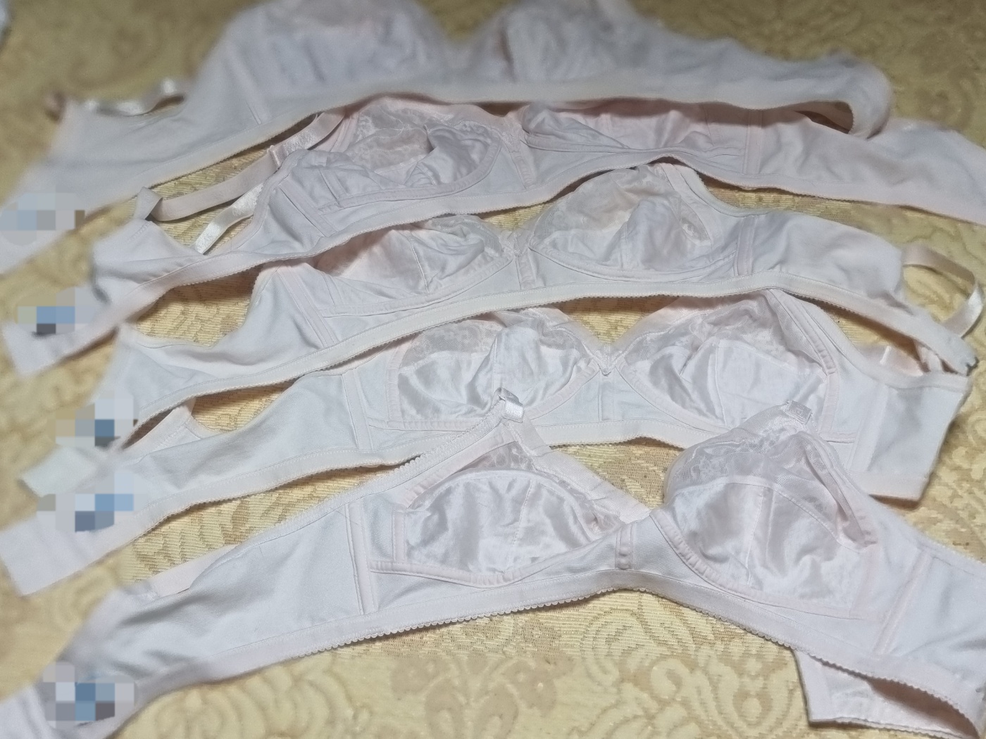 Multiple worn Korean bras laid out, showing variations in fading and wear over many years of use.