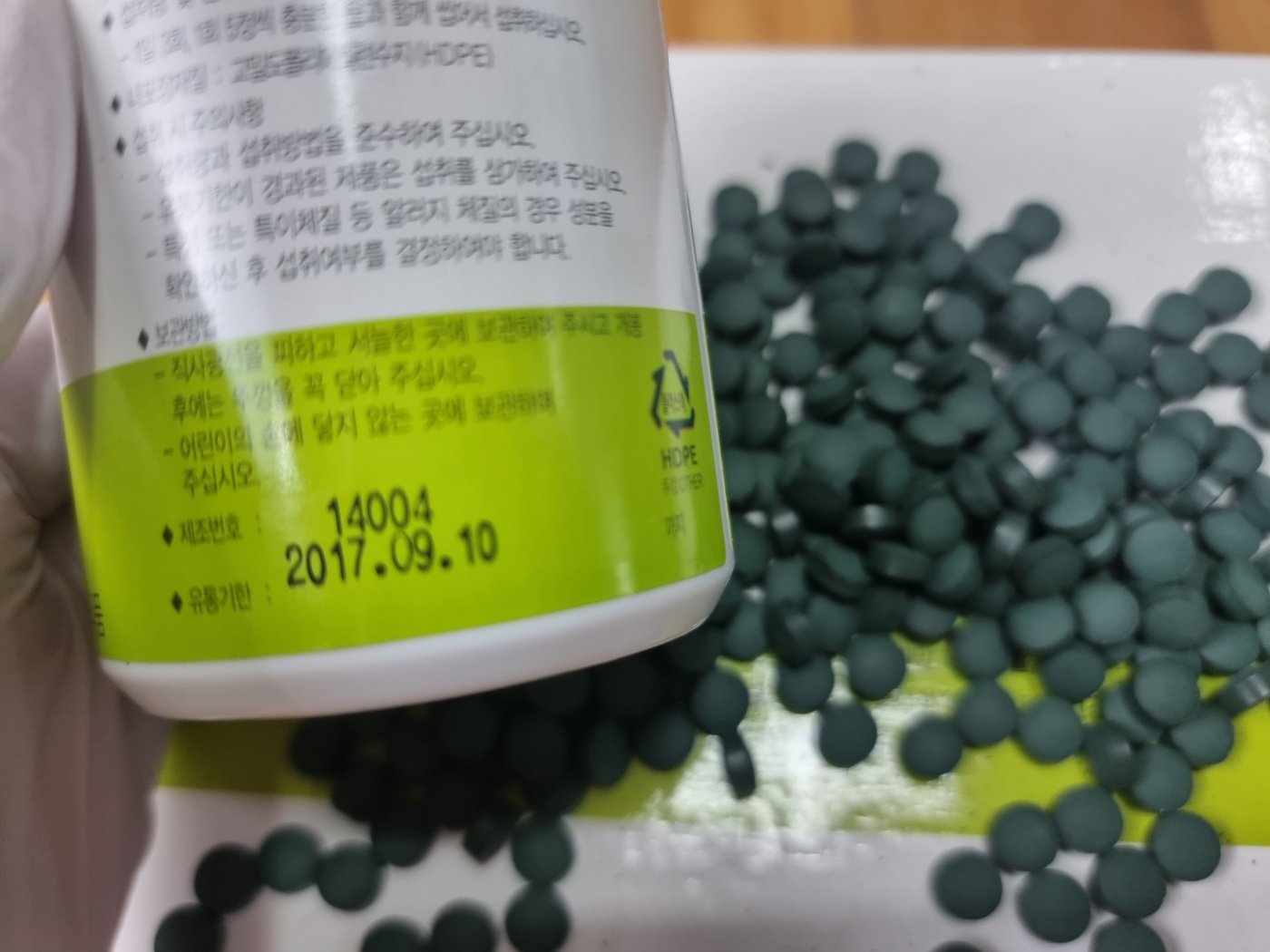 A photo of one of the opened bottles, showing the spirulina tablets and the 2017 expiration date on the bottle.